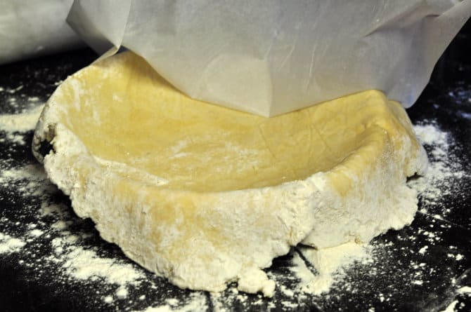 peeling off parchment paper from a homemade pie crust