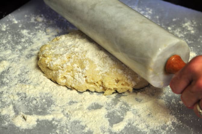 rolling out homemade pie crust dough with a rolling pin