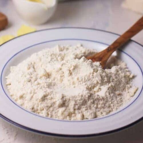 Homemade Baking Mix shown in white bowl with wooden spoon.