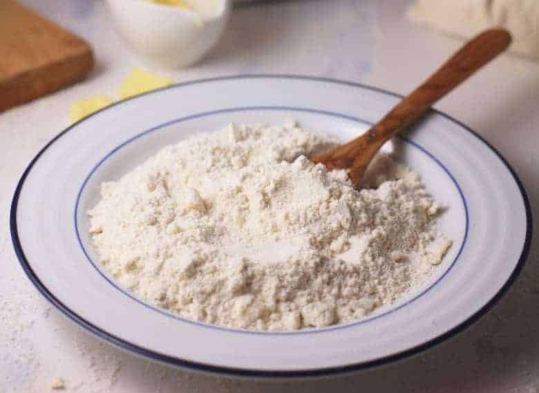 Homemade Baking Mix shown in white bowl with wooden spoon.