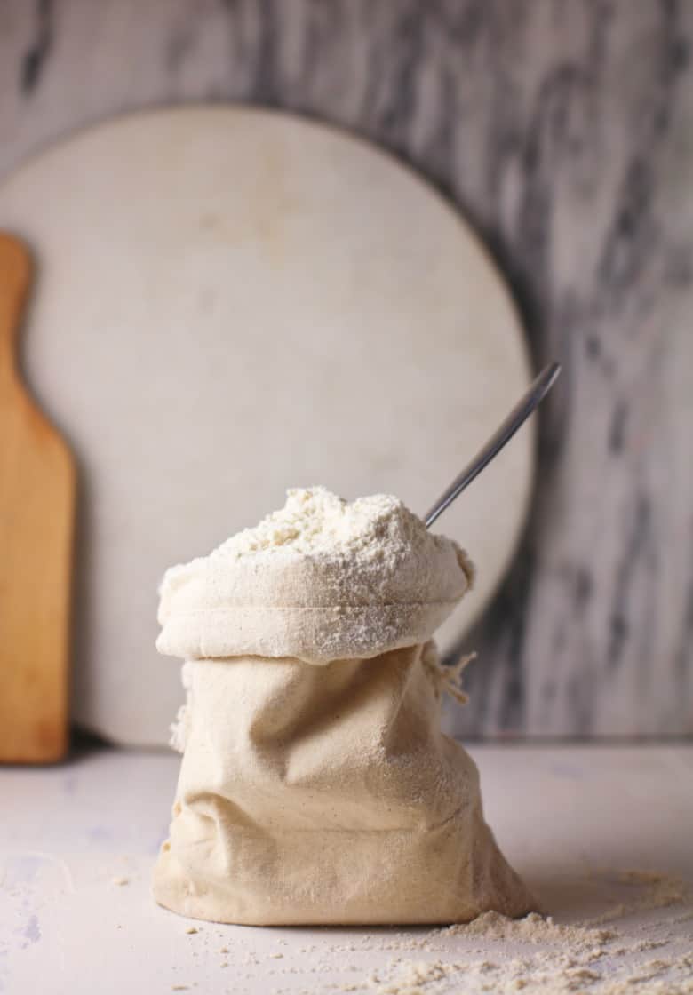 Homemade Bisquick shown ready to use in muslin bag with a spoon.