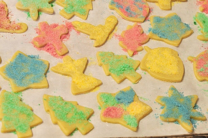 An overhead shot of homemade sugar cookies ready to bake on a tray covered with colored sugar