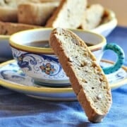 Homemade Pecan Biscotti Recipe shown stacked on blue table with cup of coffee