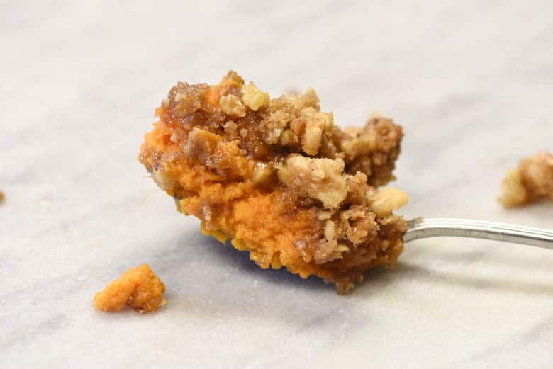 Sweet Potato Souffle Recipe, also known as Sweet Potato Casserole recipe on a spoon. It has a brown sugar topping complete with nuts - its a delicious sweet potato recipe. #myculturedpalate #sweetpotatorecipe #sweetpotato #brownsugar #holiday