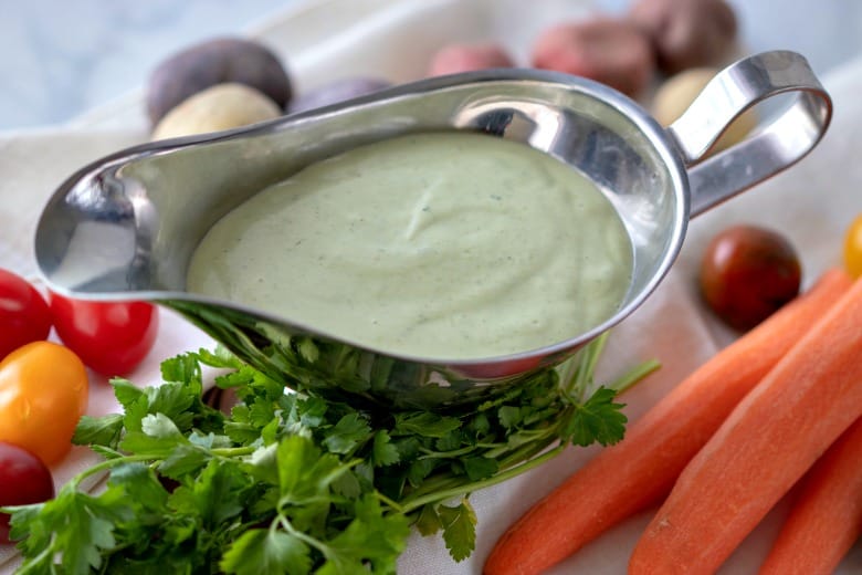 Green Goddess Dressing Recipe shown in silver pouring dish with veggies around it.