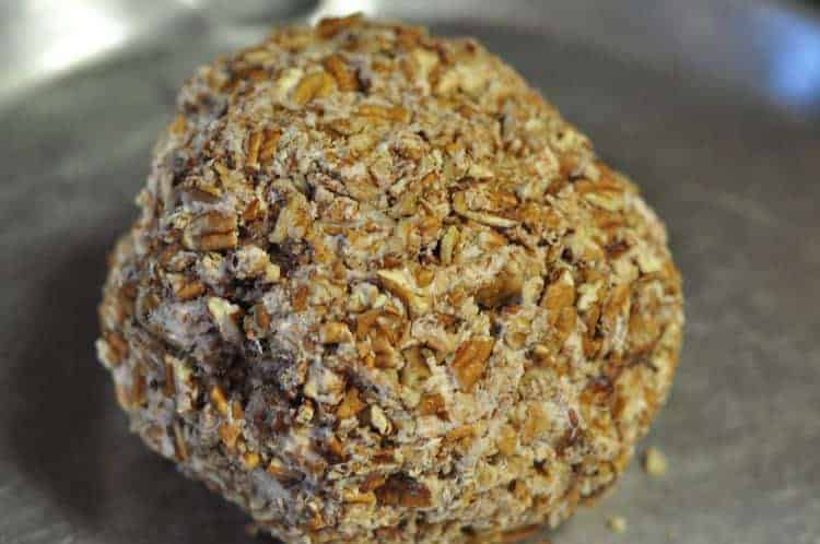 A close up shot of a salmon ball rolled in chopped nuts on a plate