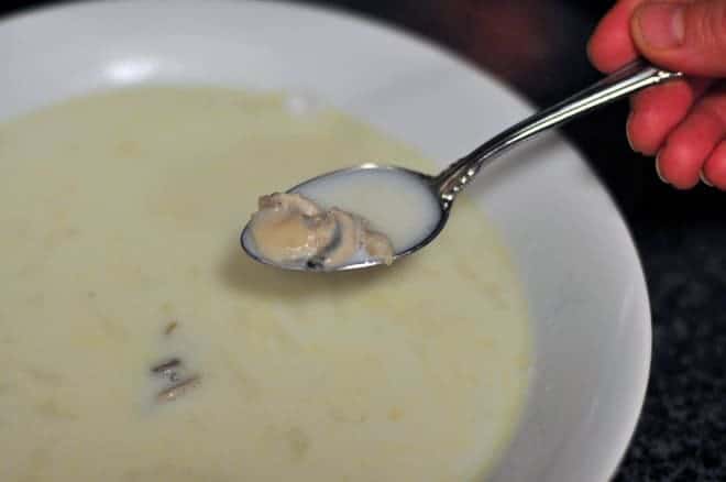 Oyster stew made from Oyster Stew Recipe in a bowl and a spoon holding one oyster