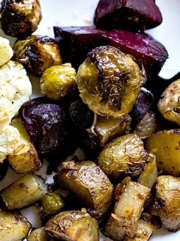 Roasted vegetables shown on white plate with black fork.
