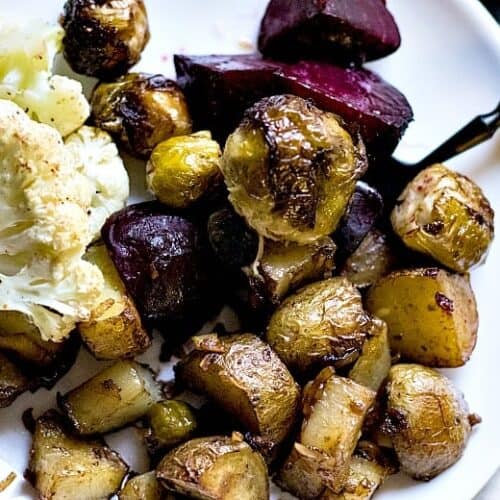 Roasted vegetables shown on white plate with black fork.