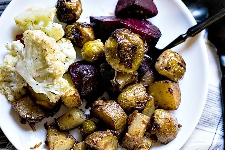 Roasted vegetables shown on white plate with black fork.