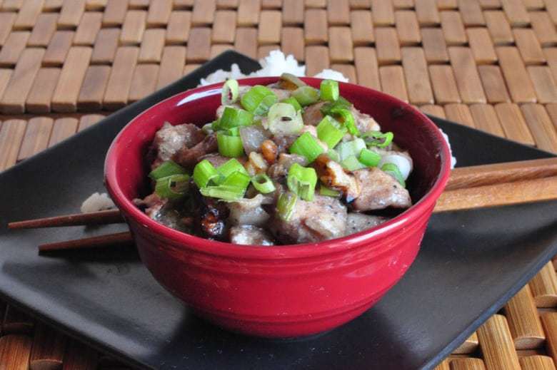 A bowl of Chinese Chicken and walnuts in a small red bowl