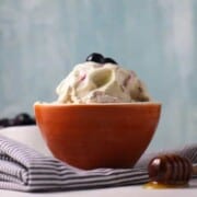 Blueberry Ice Cream shown in orange bowl on striped napkin.