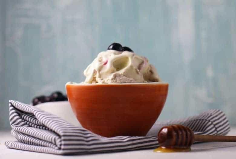 Blueberry Ice Cream shown in orange bowl on striped napkin.