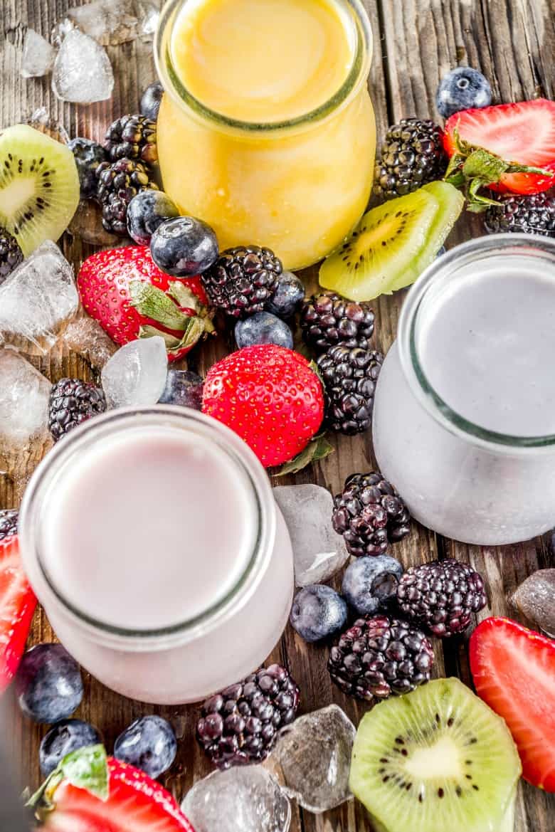 Overhead view of kefir smoothie in three flavors with fruit around.