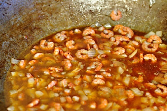 Tomato sauce added to shrimp in a wok