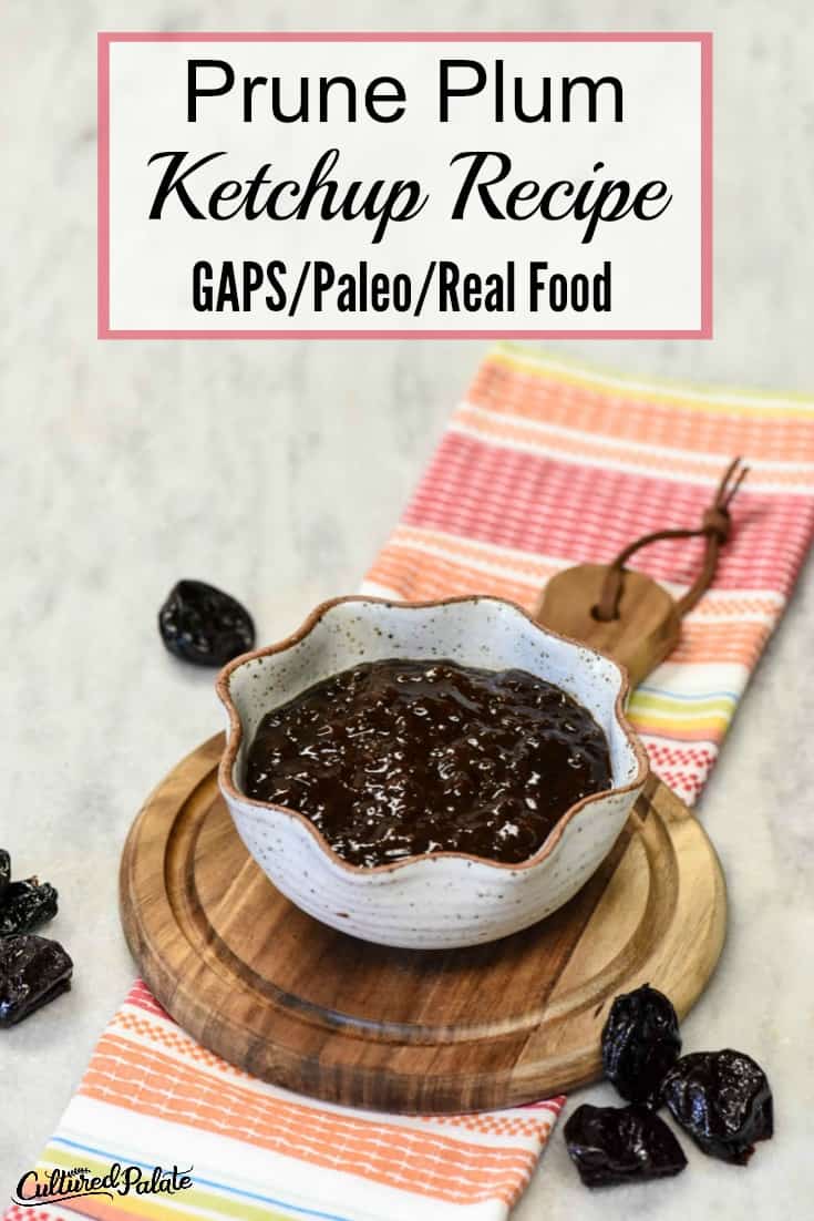 Vertical image of Prune Plum Ketchup in a bowl with prunes around it on a marble table with a bright colored napkin underneath.