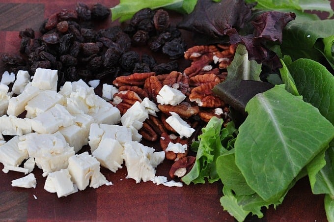a close up of ingredients to make a feta salad on a chopping board