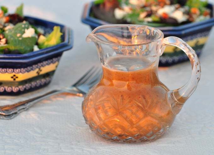Homemade raisin vinaigrette dressing in a large glass jug on a table