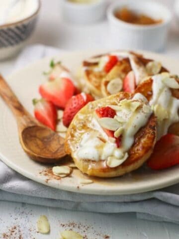 Yogurt Sauce on English Muffin French Toast on white plate topped with strawberries