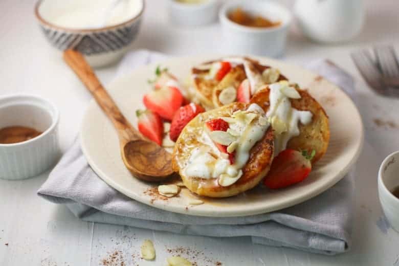 Yogurt Sauce on English Muffin French Toast on white plate topped with strawberries