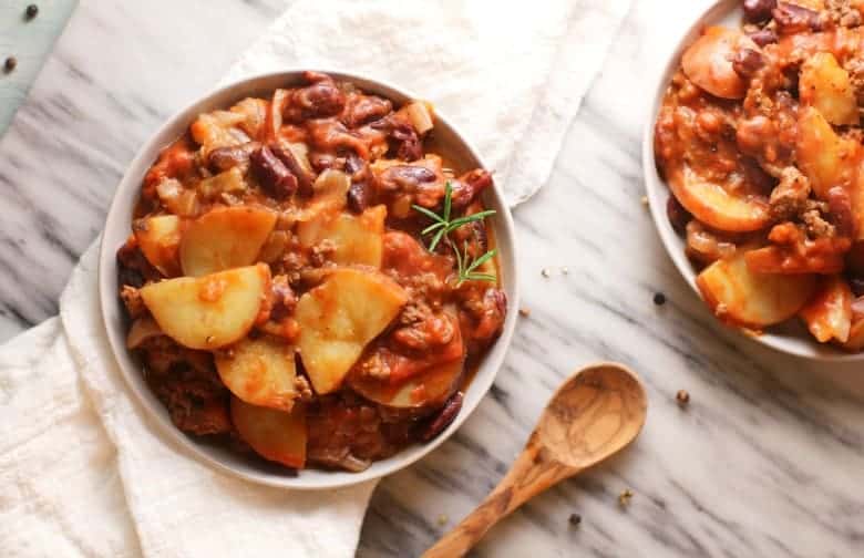 Crockpot Chili Recipe shown in white bowl from above on marble background.