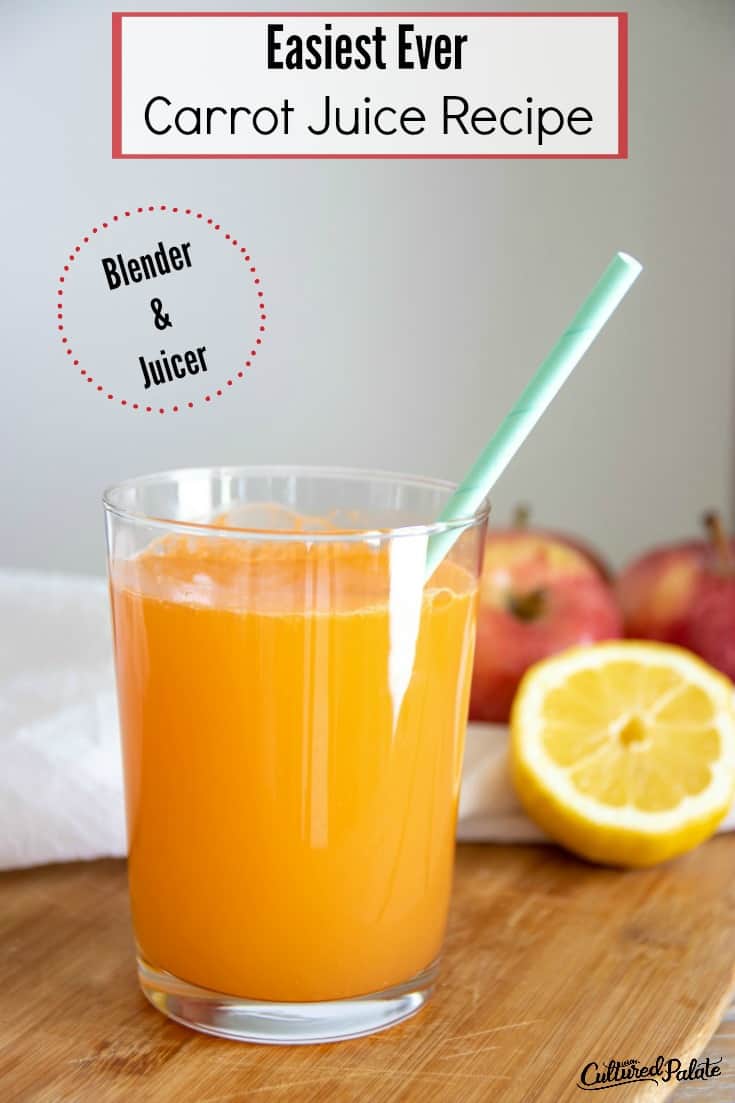 Glass of carrot juice recipe with straw and apples and lemons in background.