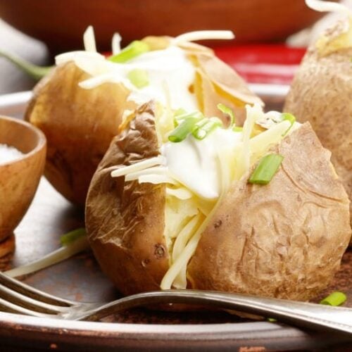 Baked Potatoes in Crock Pot shown in closeup image with fork on a plate.