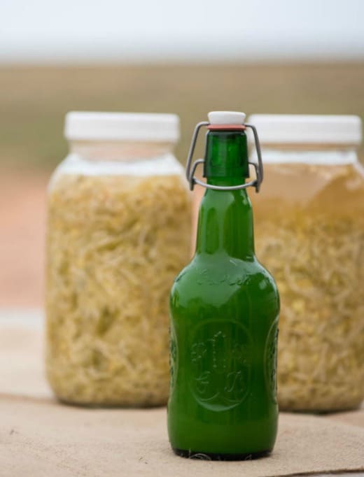 Master Tonic Bottled with Jars of Master Tonic Fermenting in the background