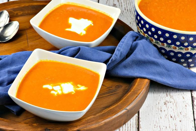 Two bowls of Moroccan Carrot Soup on wooden serving tray