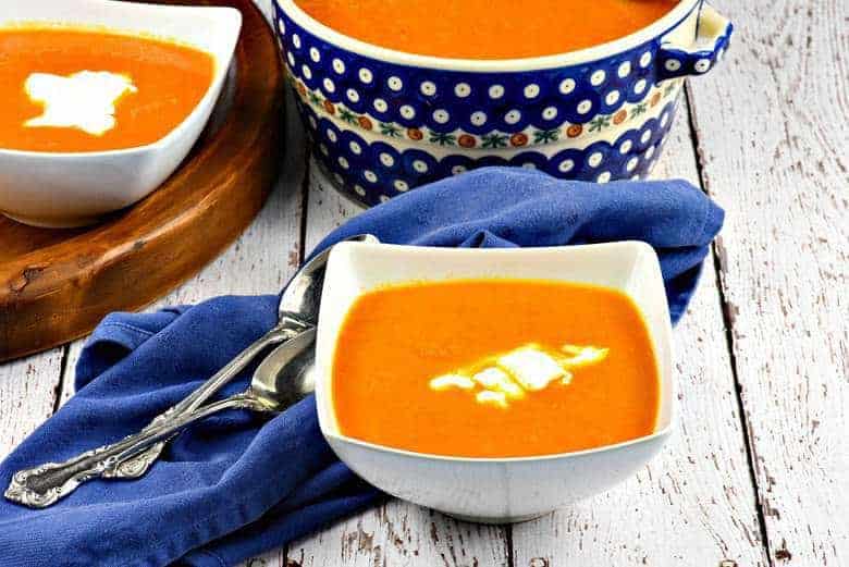 Moroccan Carrot Soup in a white bowl with two bowls in the background