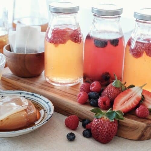 Flavored Kombucha shown in jars with fruit and scobby around.