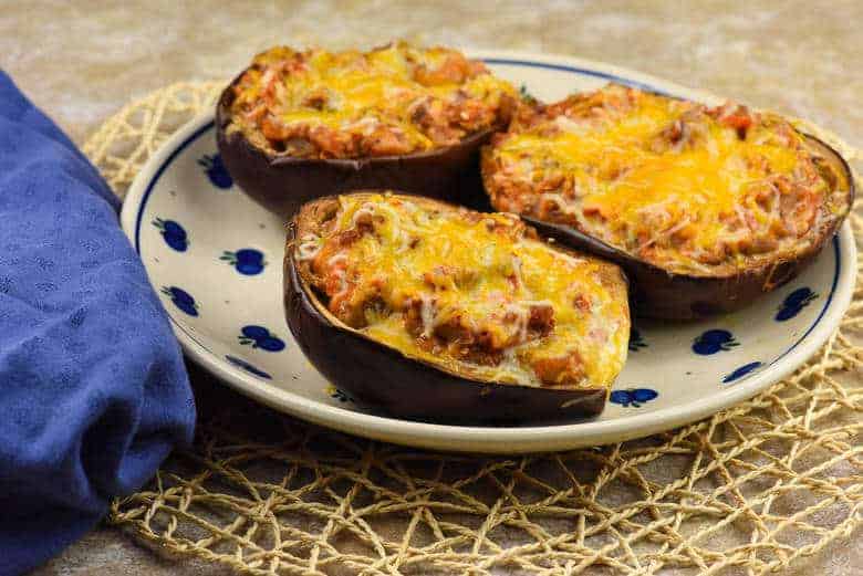 Three Stuffed Eggplants on a white and blue plate sitting on a table