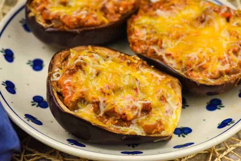 A close up of a Stuffed Eggplant topped with cheese and on a white plate