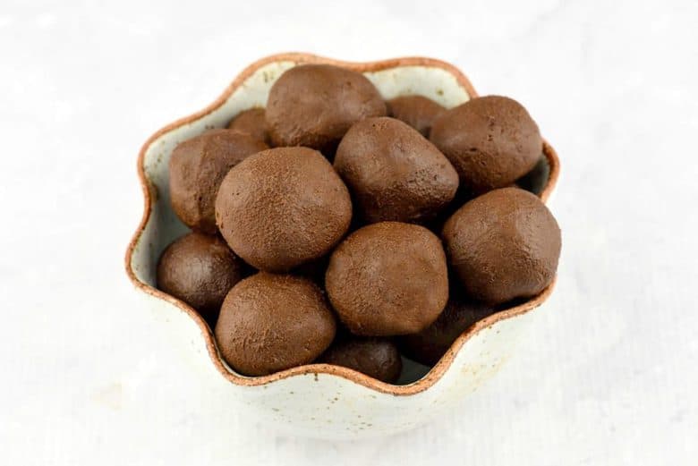 A close up of easy chocolate truffles in a bowl with scalloped edges