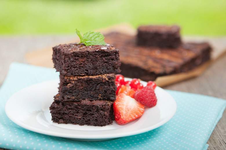 A photo of three coconut flour brownies stacked up on a white plate