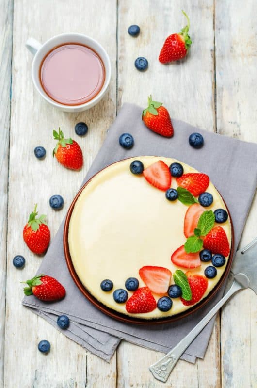 An overhead shot of the Best Cheesecake Recipe shown on a wooden surface with a cup of tea