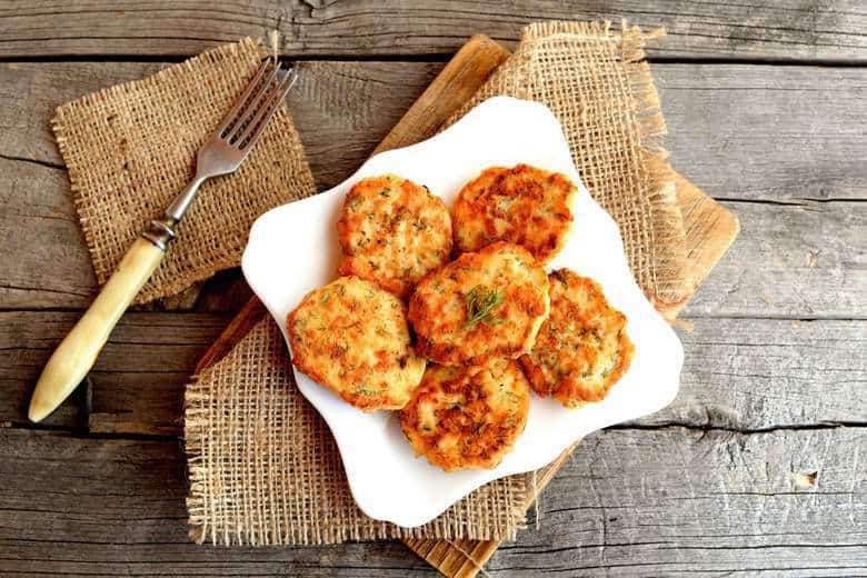 An overhead shot of Baked Salmon Croquettes on a white plate sitting on a wooden surface