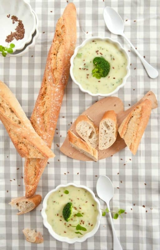 Best Broccoli Soup Recipe - Healthy Broccoli Soup shown in white bowls on table with bread and spoons