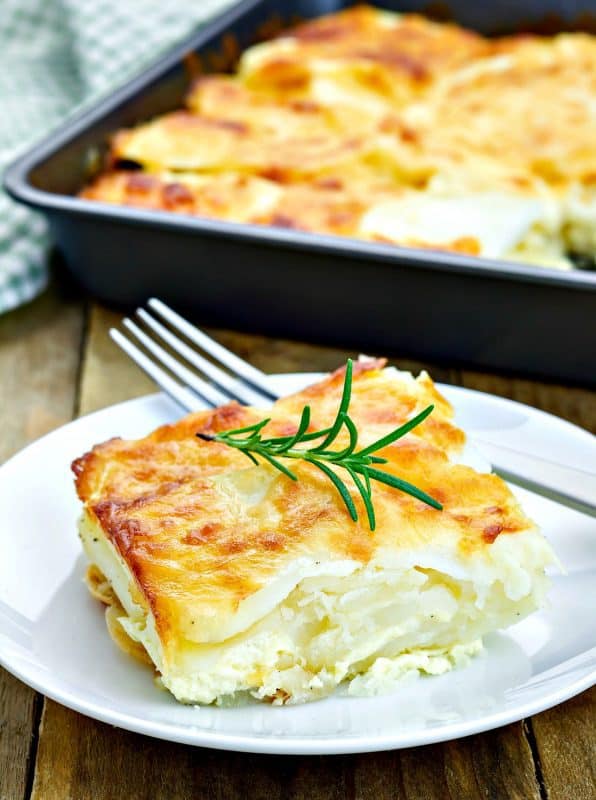 Easy Scalloped Potatoes shown on white plate with fork on table