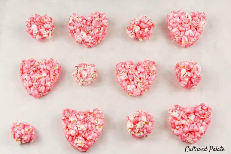 Big and small heart shaped popcorn balls on a white surface made from popcorn balls recipe