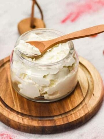 Whipped Body Butter Recipe made and shown in glass jar with candles and sppon