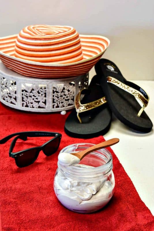 homemade sunscreen, DIY sunscreen shown with sun hat, beach towel, sunglasses and flip flops shown vertical image