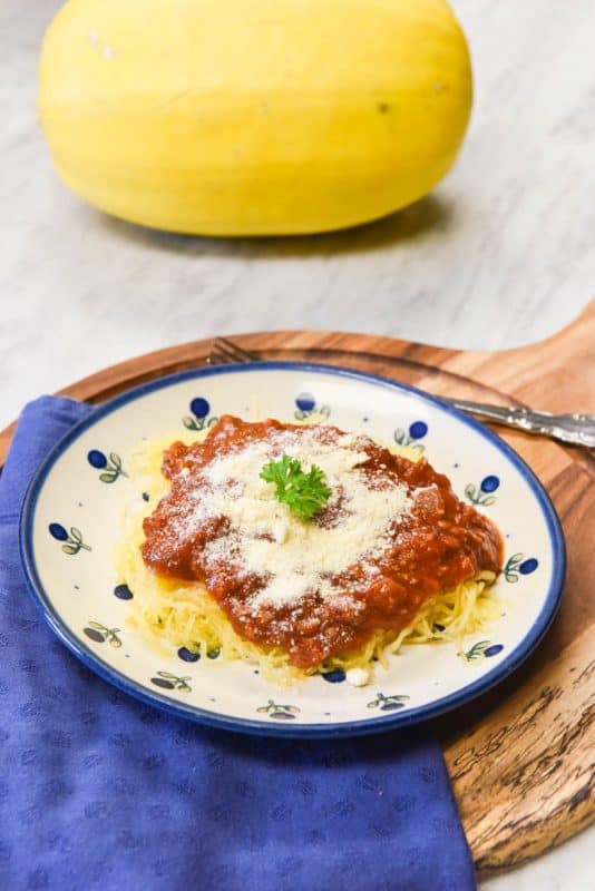 vertical image of Instant Pot Spaghetti Squash on plate ready to eat with tomato sauce on top