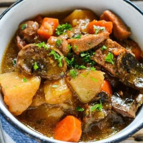 white bowl with pork stew made in the instant pot on a wooden table with white napkin