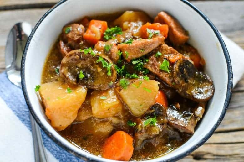 white bowl with pork stew made in the instant pot on a wooden table with white napkin