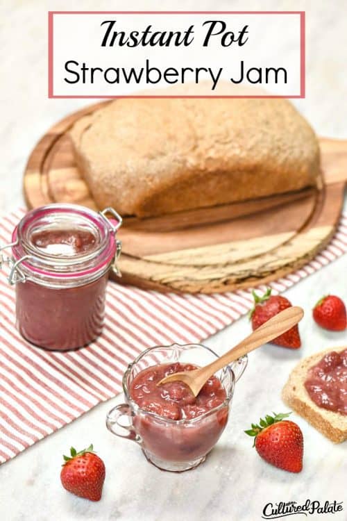 Instant Pot Strawberry Jam Recipe shown in a glass bowl with strawberries and a loaf of bread on a wooden board in background