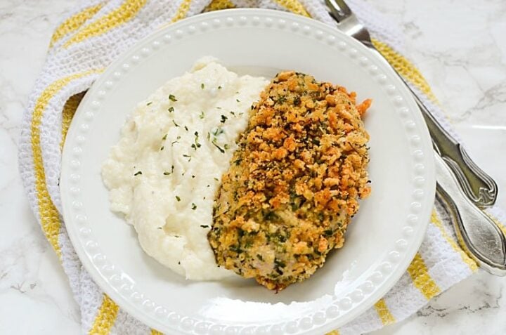Horizontal image of a breaded pork chop with cauliflower mashed potatoes on marble background