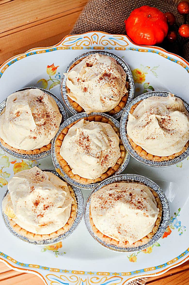 Vertical image of a plate of mini pumpkin pies on a wooden background
