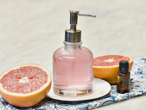 Homemade Body wash shown pink in a glass dispenser with two halves of grapefruit to either side