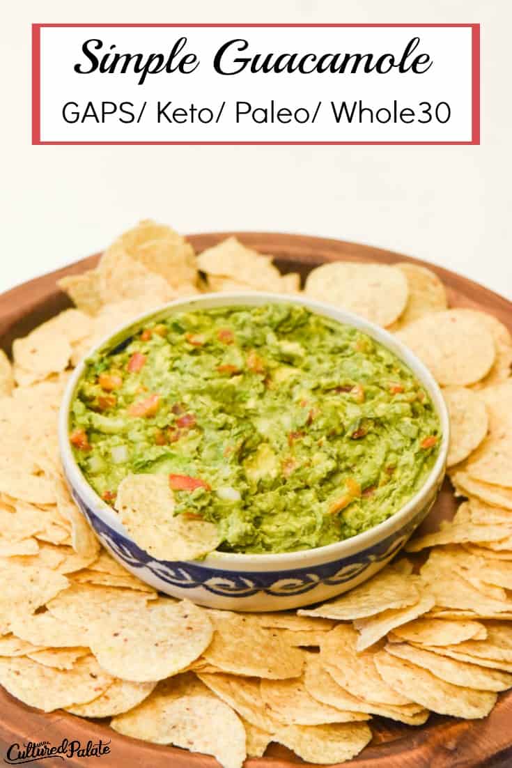 Vertical image of avocado dip from the Simple Guacamole Recipe shown in a bowl surrounded by chips on a wooden board